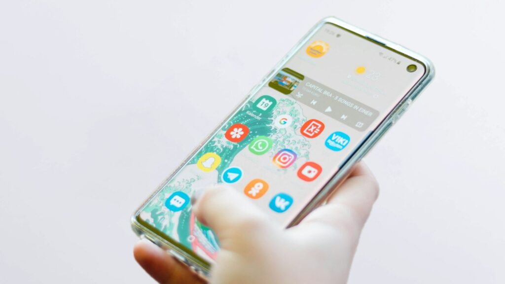 Ranka laiko išmanųjį telefoną su mobiliojo ryšio signalo juostelėmis, simbolizuojančiomis 5G palaikymą