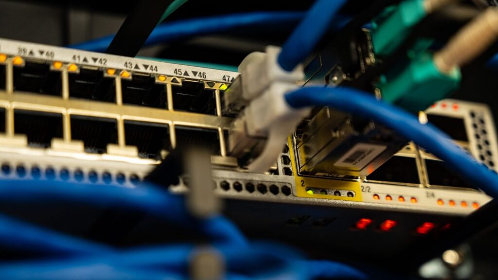 Nešiojamas kompiuteris su interneto greičio matavimo rodmenimis šalia Wi-Fi maršrutizatoriaus