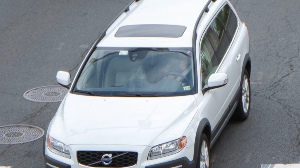 Sidabrinis Volvo XC70 universalas važiuoja žvyrkeliu tarp medžių