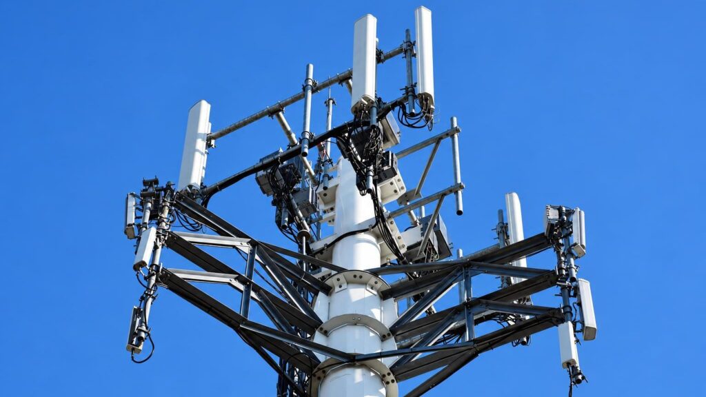Telekomunikacijos bokšto antena su belaidžio ryšio signalais prieš dangų