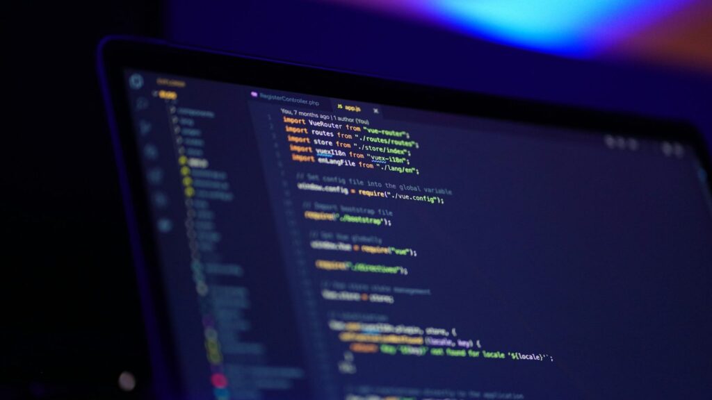 Programuotojas dirba prie nešiojamojo kompiuterio su kodu ekrane, ilgalaikė IT specialisto karjera