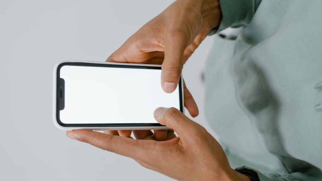 Ranka laiko išmanųjį telefoną parduotuvėje, renkantis naują modelį