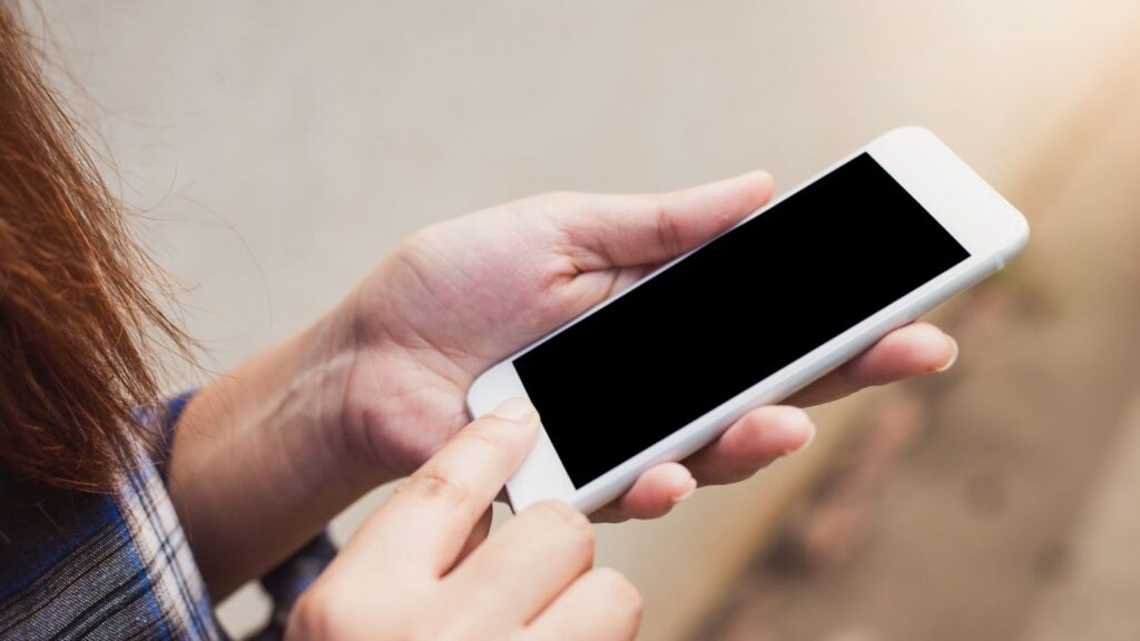 Ranka laiko išmanųjį telefoną su signalo juostelėmis lauke, mieste