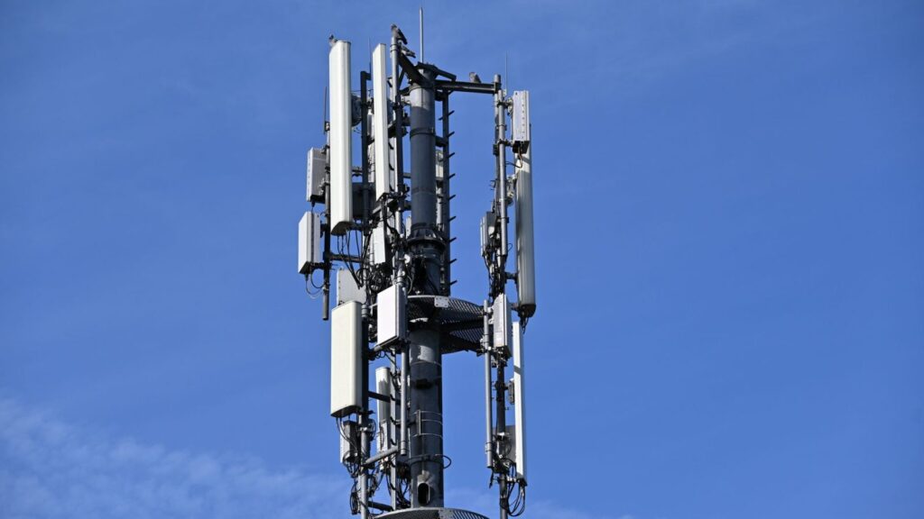 Žmogus lauke laiko telefoną ir bando sugauti mobiliojo ryšio signalą