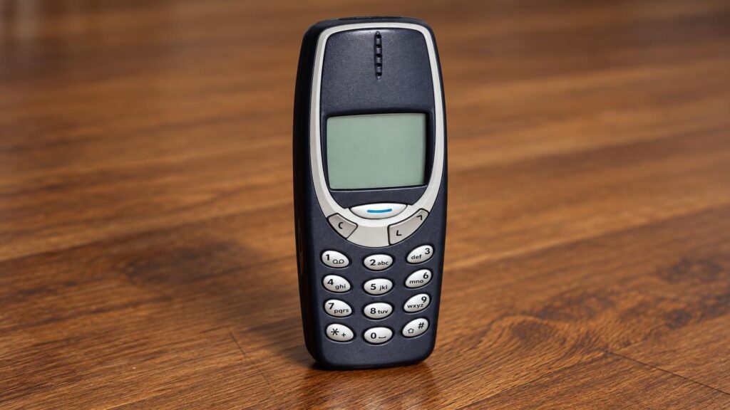 Ranka spaudžia skambinimo mygtuką senesnio mobiliojo telefono klaviatūroje