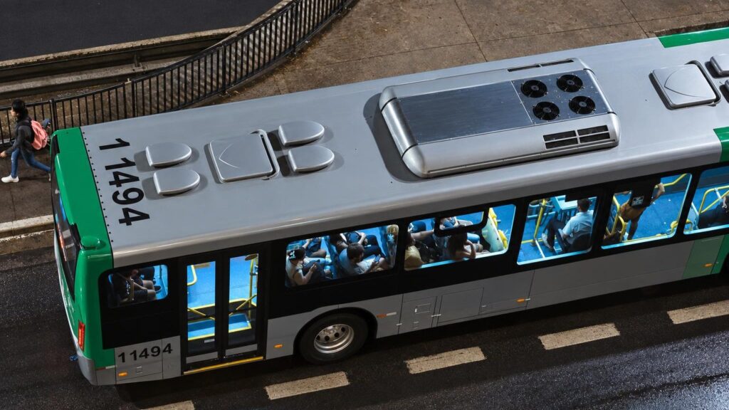 Miesto autobusas su antenomis ant stogo, keleivis naudojasi telefonu