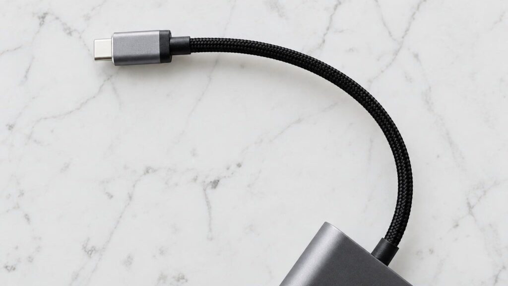 USB-C kabelis, įkištas į nešiojamojo kompiuterio jungtį – Thunderbolt 4 ir USB 4 skirtumai