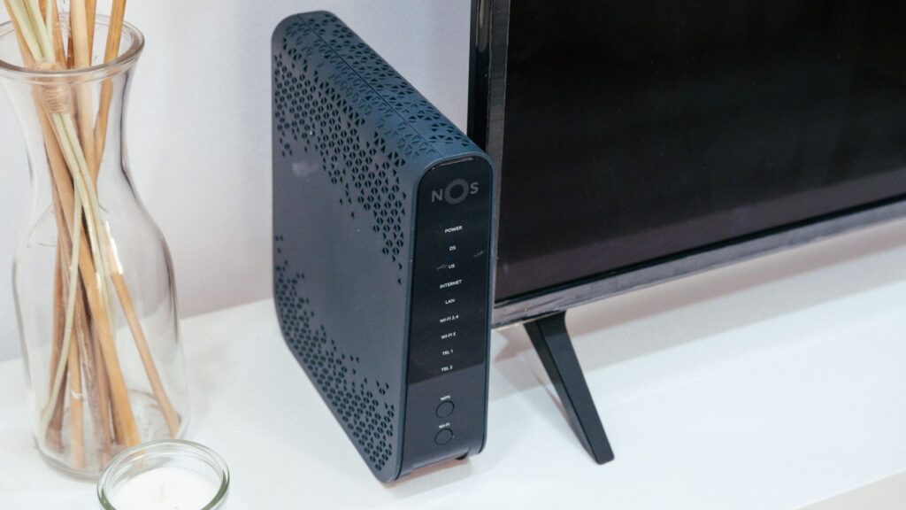 Trys baltos mesh WiFi įrenginiai ant medinės lentynos šviesiame namų interjere