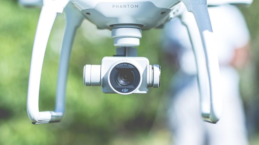 Dronas su kamera skrenda virš žalios pievos saulėlydžio šviesoje