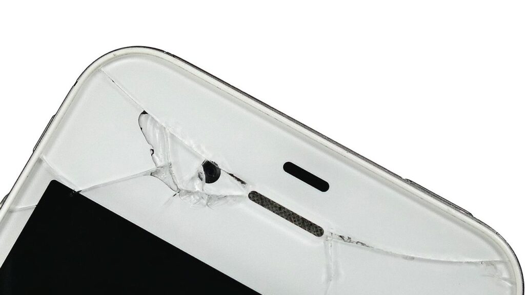 Įskilusio ekrano išmanusis telefonas ant stalo – elektronikos draudimo ir remonto tema